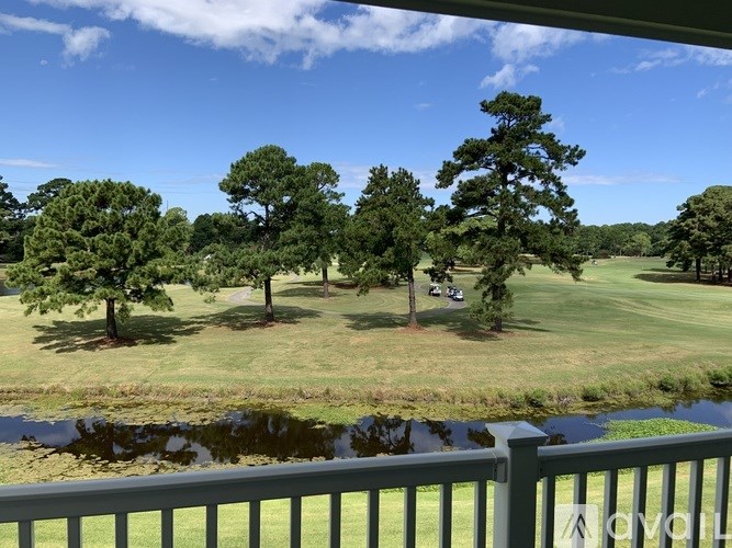 A pond is in the foreground of a grassy field with trees.