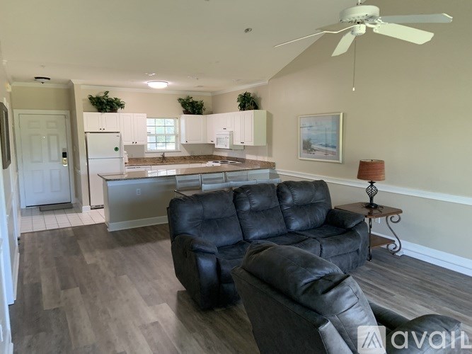A black leather chair is in the middle of a kitchen and living room.