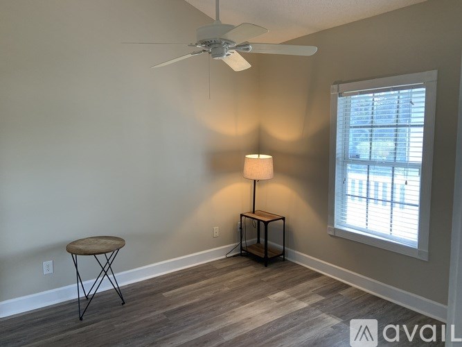 A room with a table, a lamp and a fan.