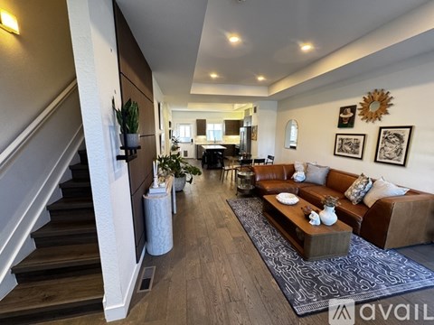 A living room with a brown couch and a staircase on the left side.