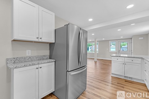 A modern kitchen with a stainless steel refrigerator and white cabinets.