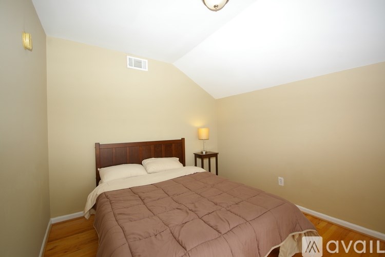 A bedroom with a bed, nightstand, and lamp.