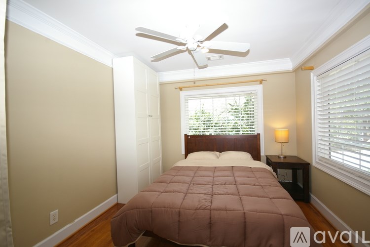 A bedroom with a bed, a ceiling fan, and a window with blinds.