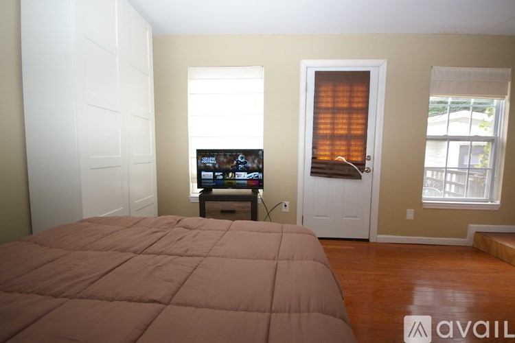 A bedroom with a bed, a television, and a window with a curtain.