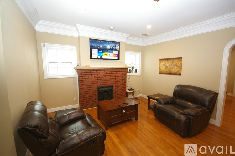 A living room with a fireplace and two leather chairs.