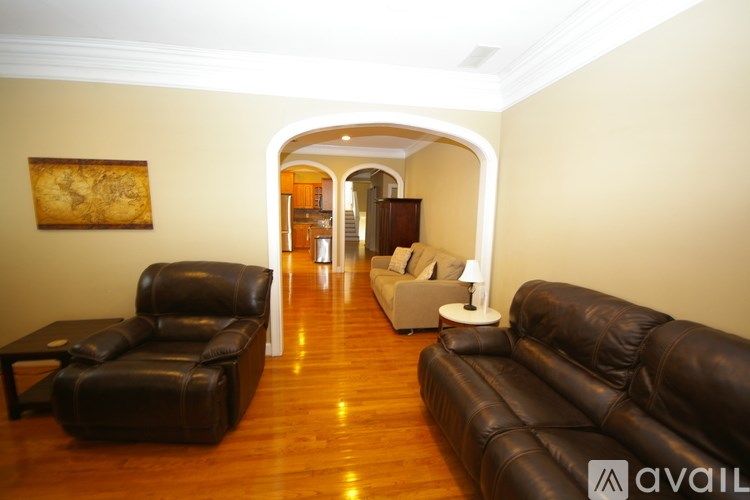 A living room with a brown leather couch and a wooden floor.