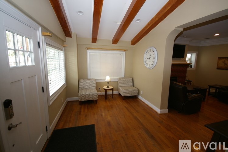 A living room with a couch, a chair, and a clock on the wall.