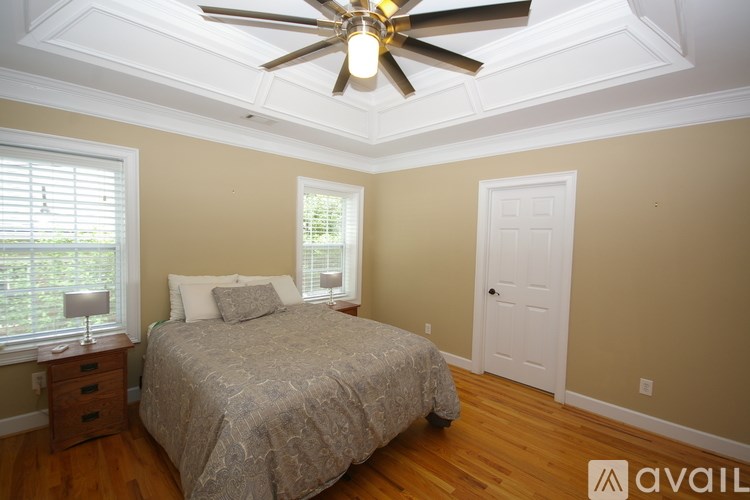 A bedroom with a bed, a ceiling fan, and a window with blinds.