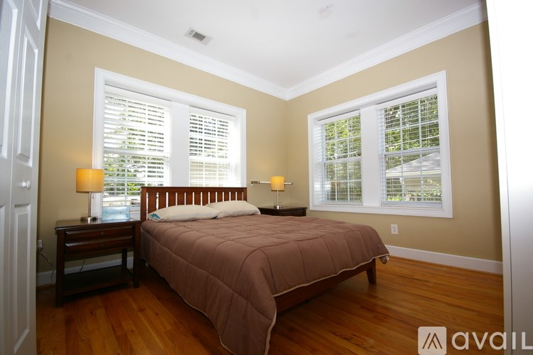A bedroom with a bed, two lamps, and a window with blinds.