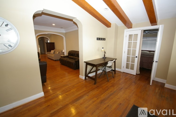A living room with a clock on the wall and a table with chairs.