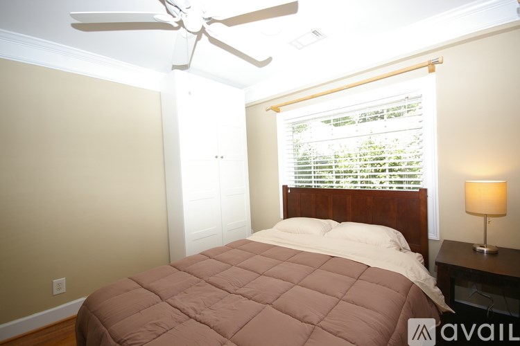 A bedroom with a bed, ceiling fan, and window with blinds.