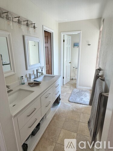 A bathroom with a sink, mirror, and towel rack.