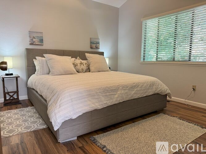 A bedroom with a large bed and a window with blinds.