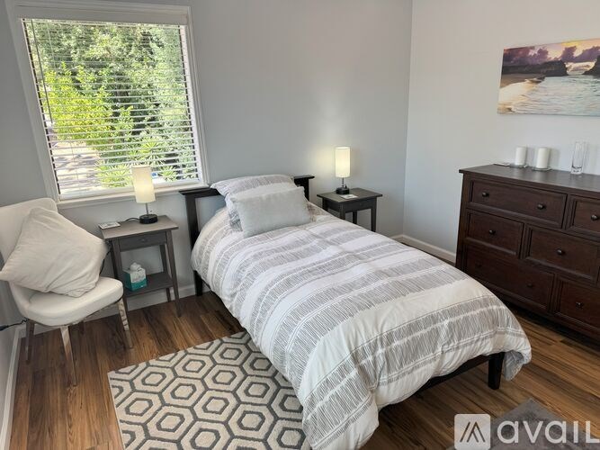 A bedroom with a bed, nightstands, and a chair.