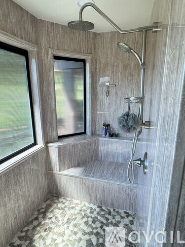 A shower area with a bench and a window.