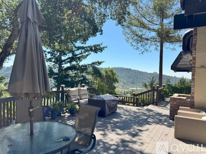 A patio with a table, chairs, and an umbrella overlooking a mountain.