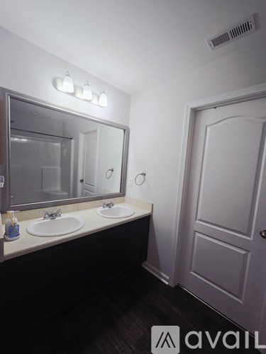 A bathroom with a mirror, sink, and door.