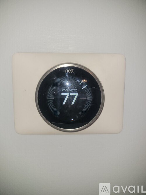 A Nest thermostat is set to 77 degrees.