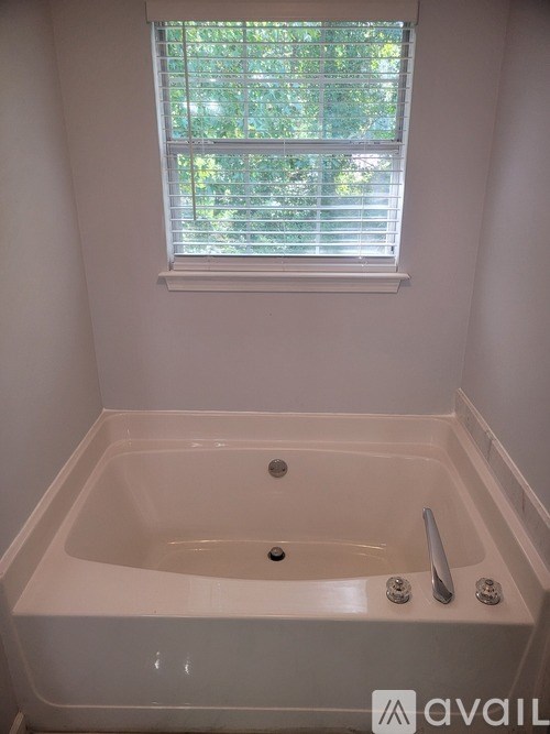 A white bathtub with a window above it.
