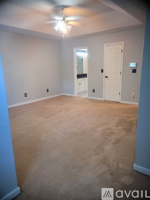 A room with a carpeted floor and a ceiling fan.
