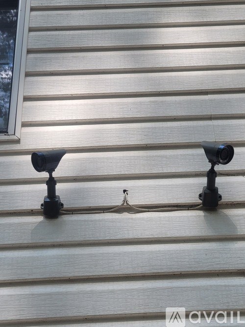 Two black security cameras are mounted on a house.