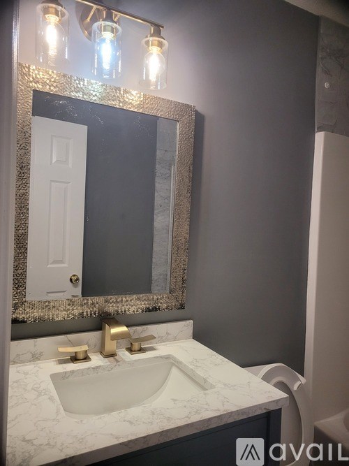 A bathroom with a marble countertop and a mirror above the sink.