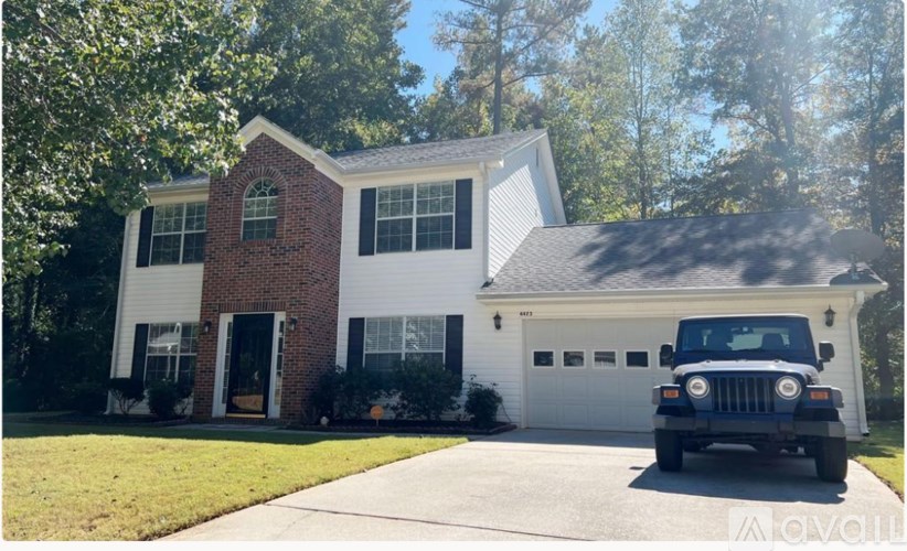 A white house with a red brick chimney and a black car in front.
