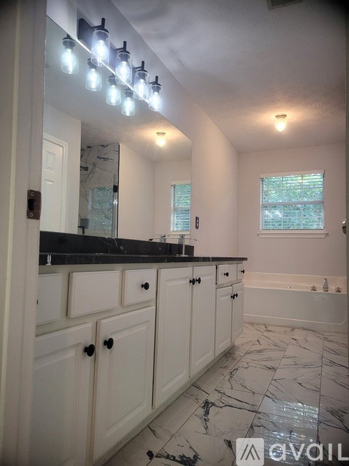A bathroom with white cabinets and a marble floor.