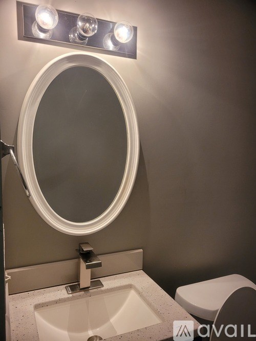 A bathroom with a round mirror, a sink, and lights above it.