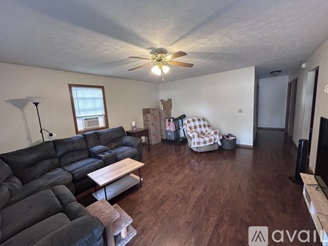 A living room with a black leather couch and a wooden floor.