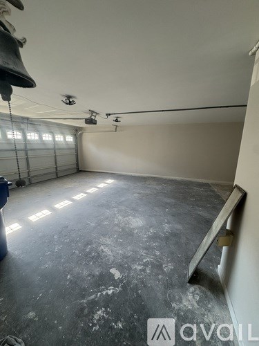 A room with a concrete floor and a white wall with a blue bin on the floor.