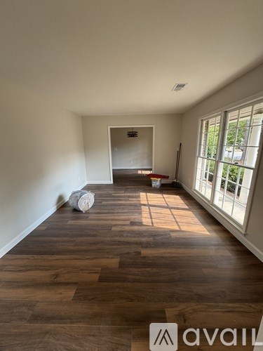 A room with wooden flooring and a window on the right side.