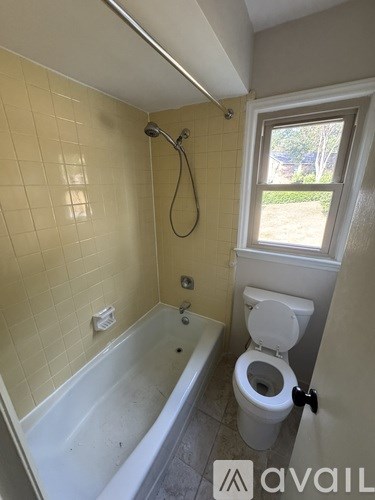 A bathroom with a toilet, tub, and window.