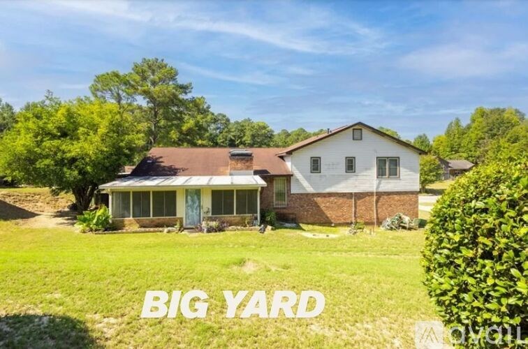A house with the words "BIG YARD" written on the grass in front of it.