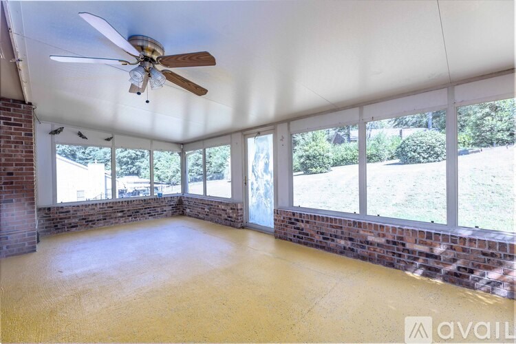 A room with a ceiling fan and large windows.