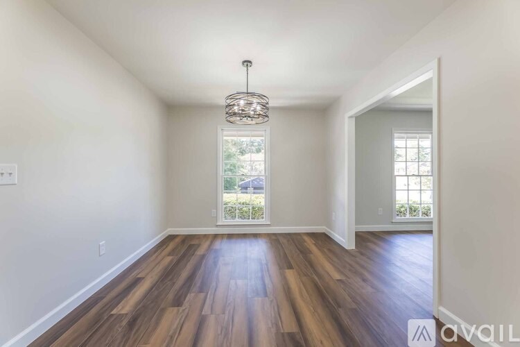 A room with wooden floors and a chandelier hanging from the ceiling.