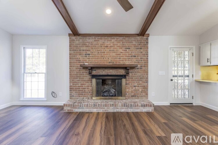 A living room with a brick fireplace and wooden floors.