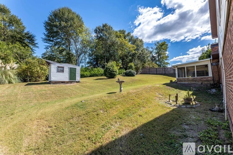 A backyard with a shed, a fence, and a tree.