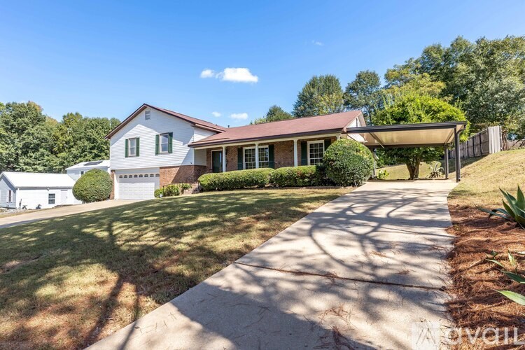 A house with a white garage door is surrounded by greenery.