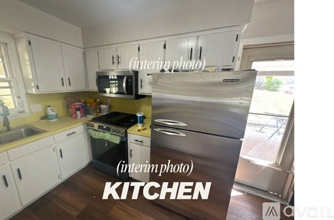 A kitchen with white cabinets and a stainless steel refrigerator.