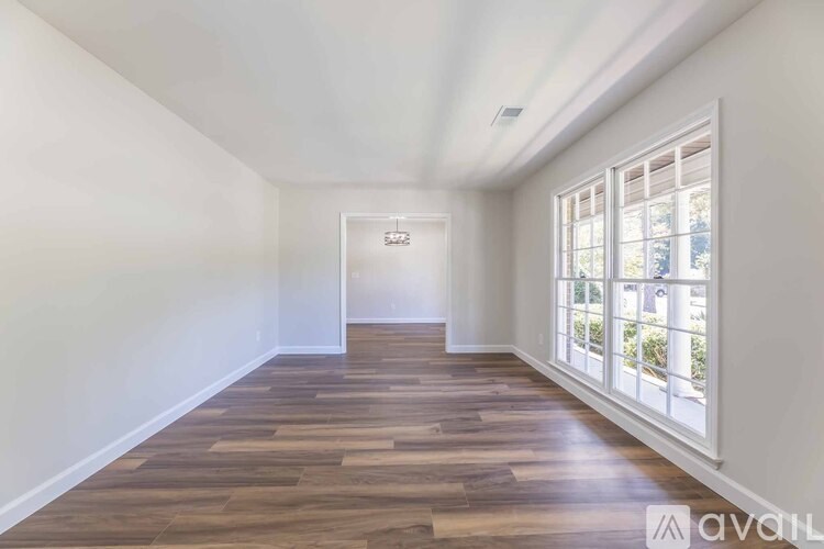 A kitchen with a black fridge and wooden floors.
