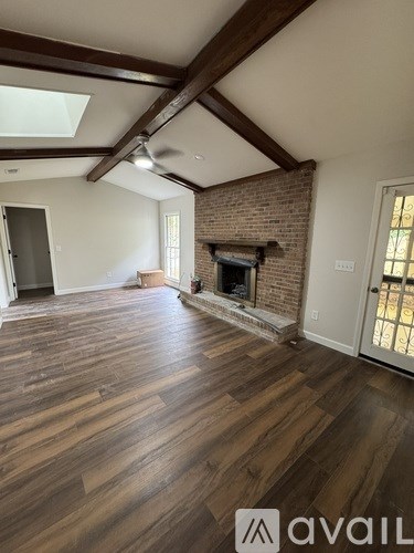 A room with wooden floors and a brick fireplace.