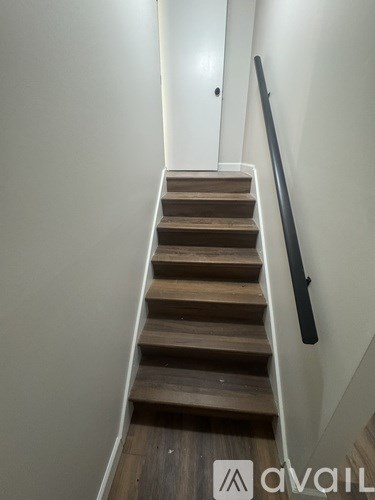 A staircase with wooden steps and a black handrail.