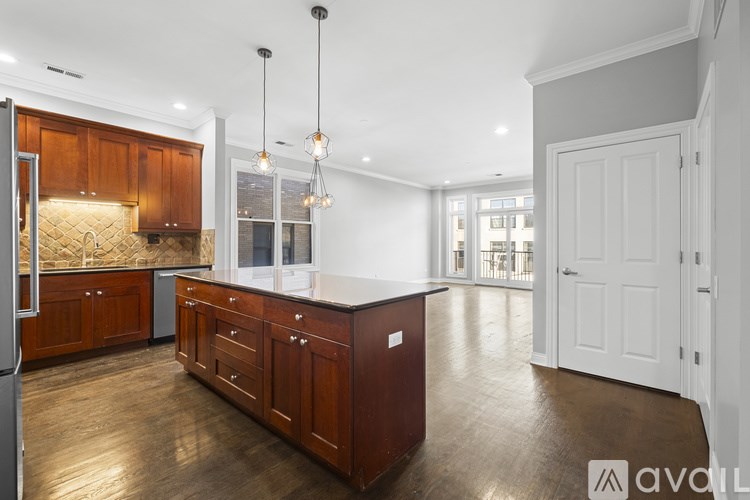 A kitchen with wooden cabinets and a countertop with a refrigerator on the left side.