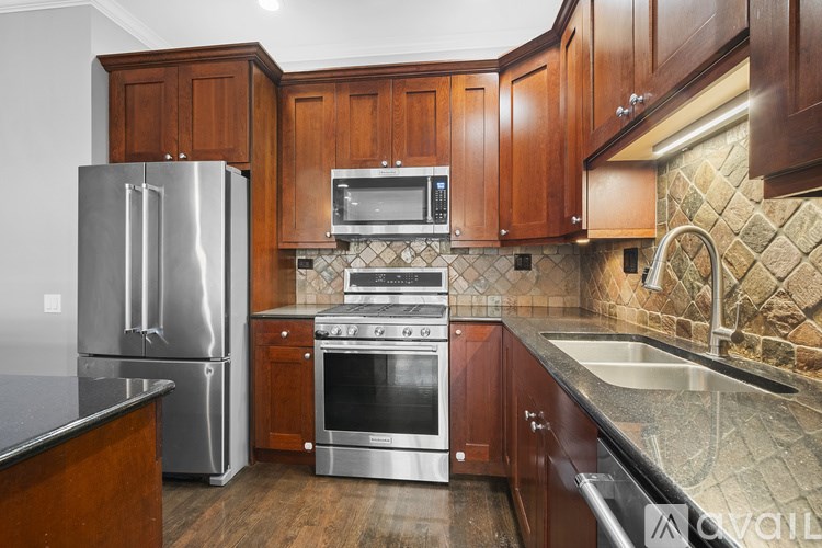 A kitchen with wooden cabinets and a stainless steel refrigerator.