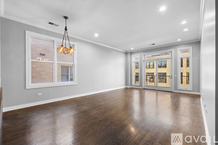 A spacious room with wooden floors and a chandelier hanging from the ceiling.