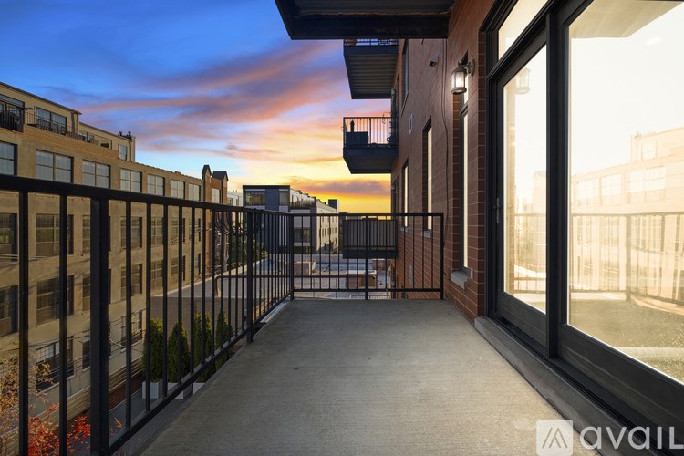 A balcony with a metal railing and a view of the city at sunset.
