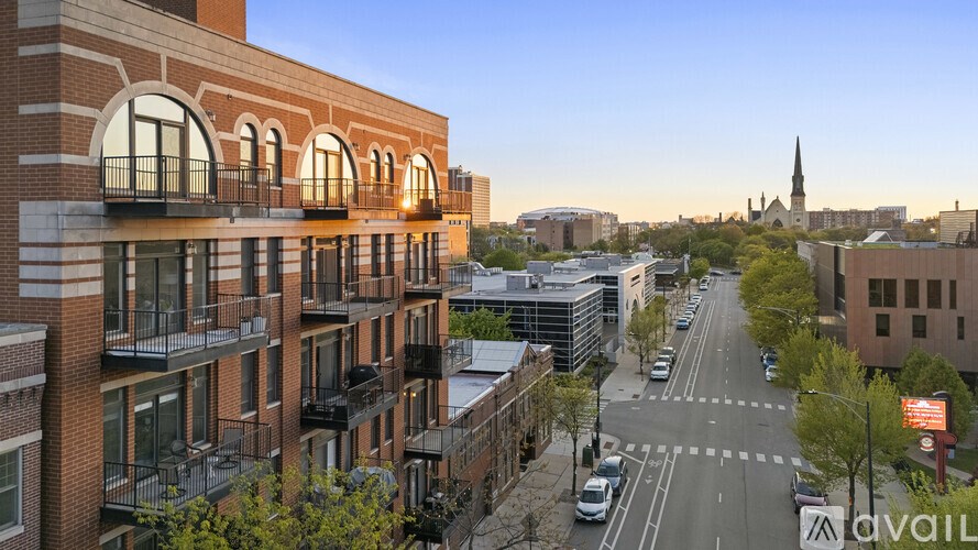 A street view of a city with a church spire in the distance.