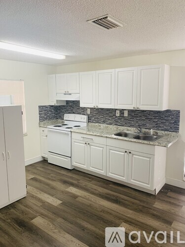 A kitchen with white cabinets and a granite countertop.