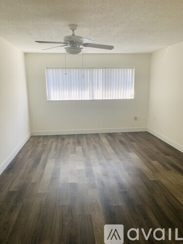 A room with a fan and wooden flooring.